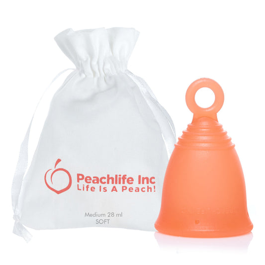 An orange silicone ring stem menstrual cup with a loop handle next to a white drawstring pouch printed with the Peachlife Inc logo and 'Life Is A Peach!'.