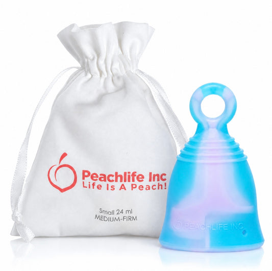 A translucent blue menstrual cup with an iridescent lavender-blue sheen, shown next to a white drawstring pouch printed with the red Peachlife Inc logo and text.
